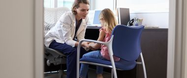 En kvinnelig psykiater snakker med en liten jente på kontoret
