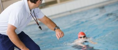 Idrettstrener sekunderer svømmer i bassenget