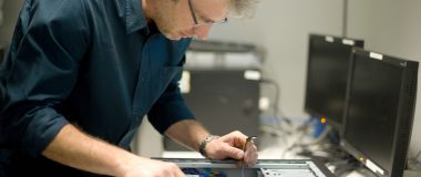 Ein mann reparerer en datamaskin.