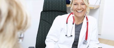 Kvinnelig lege smiler til pasient.