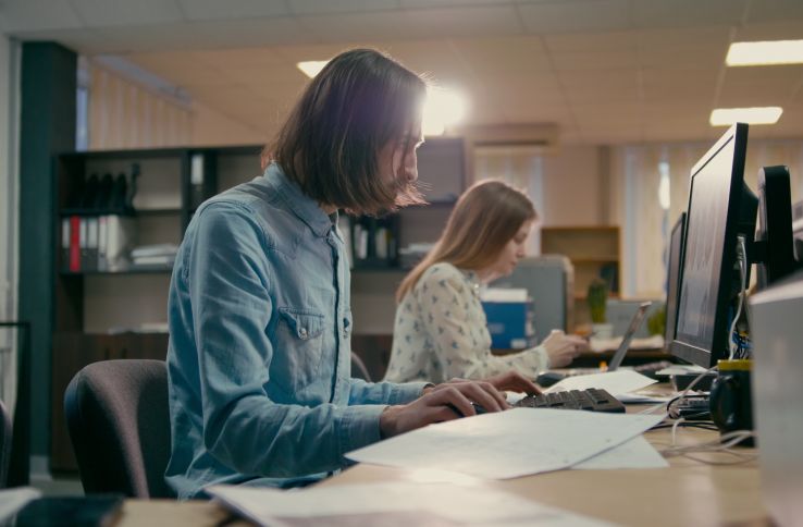 En mann og en kvinne jobber med foran datamaskiner i et kontorlandskap