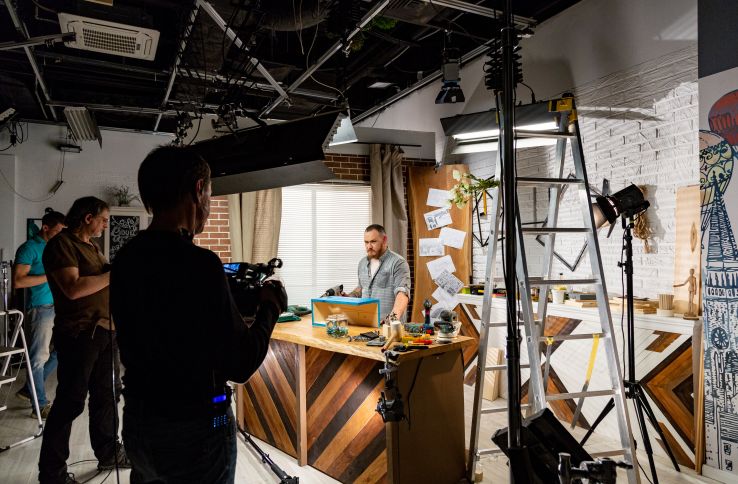 To kameramenn filmer en programleder i et tvstudio