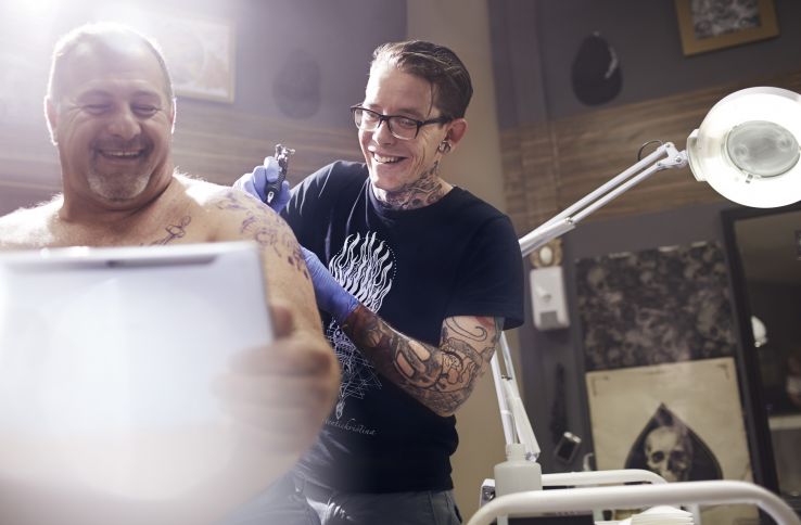 En tatovør tatoverer skulderen til en eldre mann