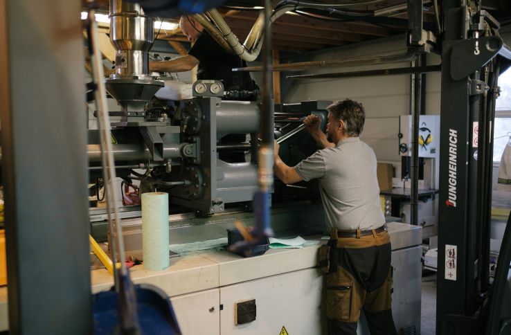 En mann i arbeidsklær med en stor skiftnøkkel i en maskin
