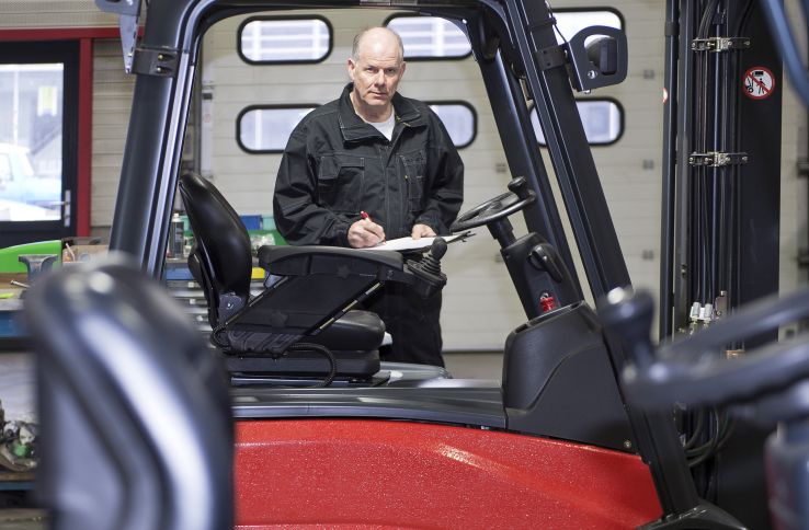 En mann står bak en truck i arbeidsklær