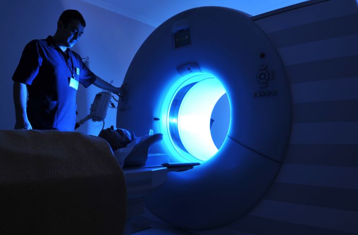 Onkologen fører ein person inn i ei strålemaskin