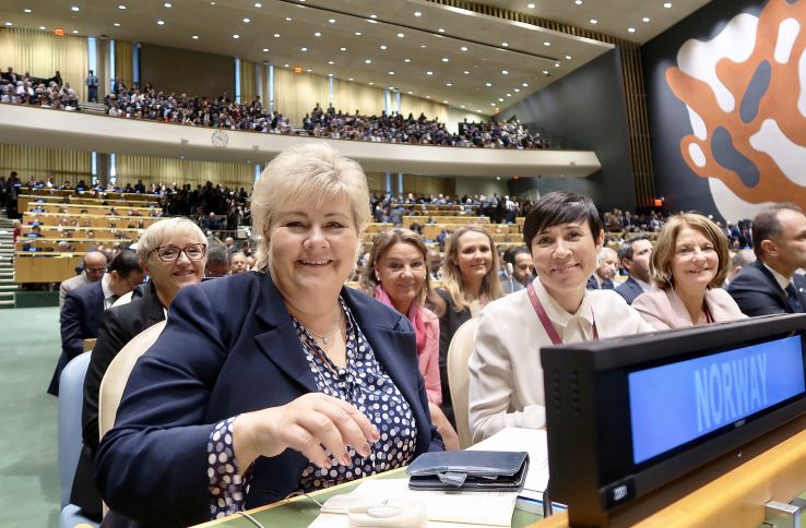 Bilde av Statsminister Erna Solberg og Utenriksminister Ine Marie Eriksen Søreide sit i ein sal saman med fleire andre menneske.