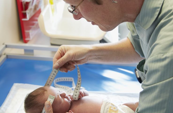 Helsesykepleier måler hodeomkretsen til nyfødt baby. 