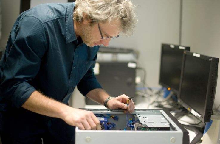 Ein mann reparerer en datamaskin.