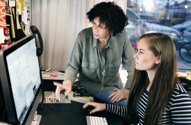 Voksen dame og ung dame jobber sammen på datamaskin