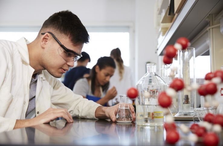 Mannlig biokjemiker studerer kjemikalie i glassflaske 