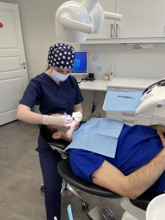 Kvinne med tannlegeklær jobber med pasient i pasientstol