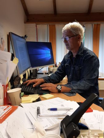 Statsviter Svein Erik Tuastad sitter på kontoret sitt med masse papir foran seg.