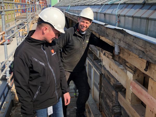 Byantikvar Magnus Borgos med hjelm står sammen med en kollega og ser på byggearbeid på et gammelt hus på Røros