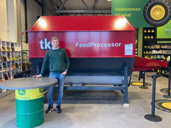 Agronom Torstein Bjerkan Klev i grønn genser foran en FeedProcessor i Felleskjøpet-butikken. Det står en John Deer-tønne ved siden av ham.