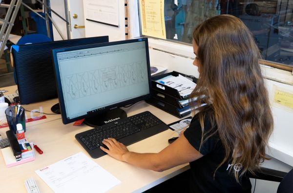 Kvinne sitter foran datamaskin og jobber med grafisk program