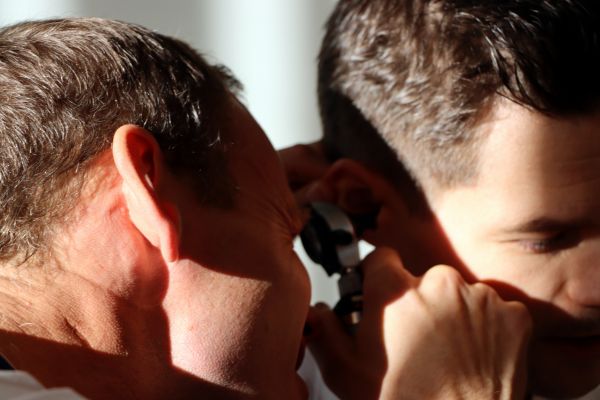 Lege Øystein Seth Fiskå sjekker ørene til en pasient. 