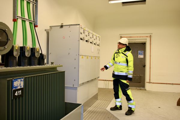 Elektroingeniør Johannes Olsen er avbildet mens han kontrollerer inne på en nettstasjon. Han er iført hvit hjelm og gul arbeidsjakke og gul arbeidsbukse.