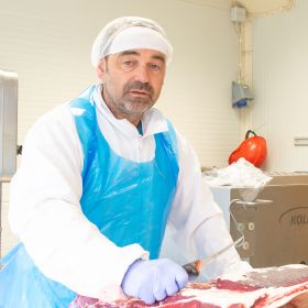 Kjøttskjærer Jan Morten i arbeidsklær holder på et stykke med ribbein