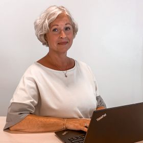 Markedsanalytiker Cecilie Natasha Henriksen i TINE sitter ved et bord med en bærbar PC foran seg.