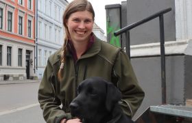 Carita på gaten i Oslo sammen med en hund som er midt i treningsopplegget for å bli en trygg førerhund.
