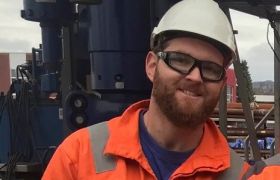 Brønnoperatør for mekaniske kabeloperasjoner Thomas Bjorland iført hjelm og orange kjeledress ute på plattform.
