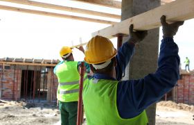 To tømrere på en byggeplass støtter en planke.
