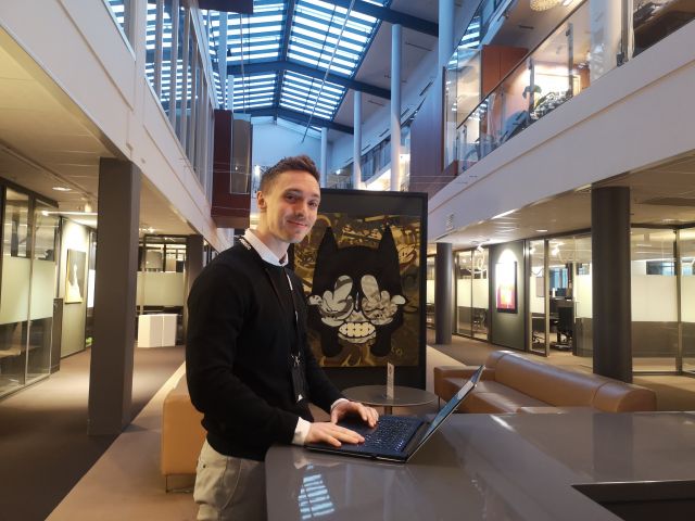 BI-Konsulent Sebastian Hollo ved pc-skjermen i et kontorlandskap med høyt under taket