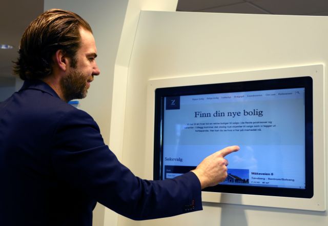 Eiendomsmegler Jørgen Nyhus sjekker eiendomsmarkedet på en dataskjerm i veggen