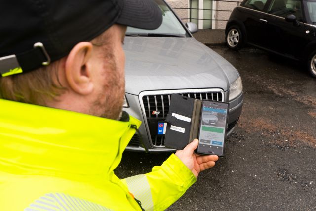 Trafikkbetjent Andrew Taylor ser på et program på mobilen sin, som hjelper han å se om bilister har betalt for parkering.