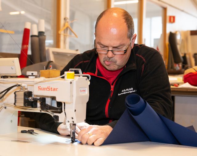 Salmaker Knut Olav Wettre bruker symaskinen til å sy på stoff.