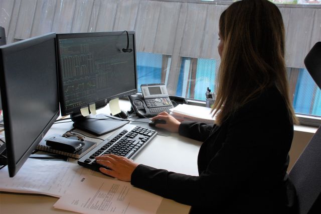Finansanalytiker Siv Merete Hagen jobber foran PC-skjermene på kontoret sitt.
