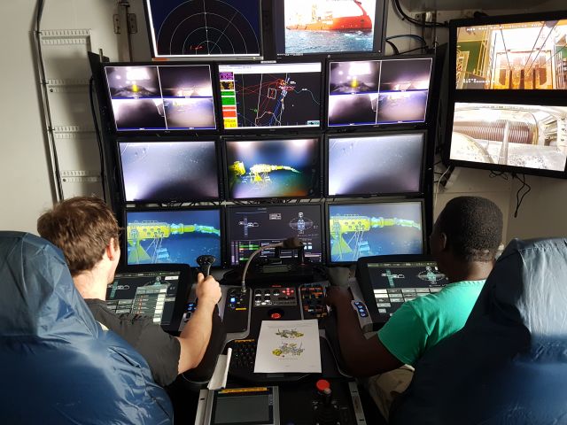 ROV-pilot Thomas Eriksen Bru sitter med en kollega foran mange skjermer hvor de kan se de undersjøiske operasjoner de jobber med.