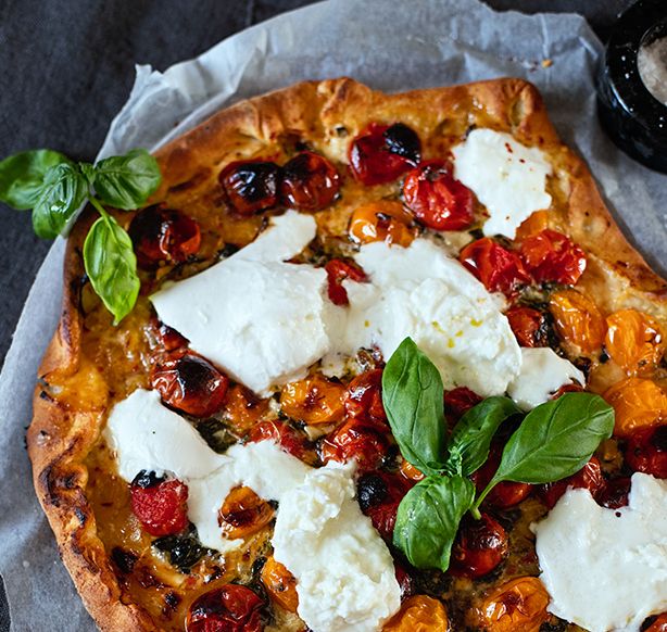 Pizza med mozzarella, tomat, oliven og frisk basilikum