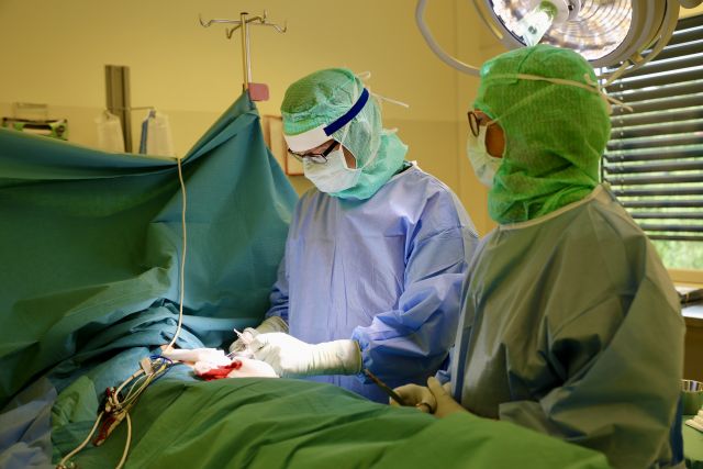 Kardiolog Jan Hysing saman med ein operasjonssjukepleiar i ein operasjonssal. Dei er kledd i grønt og står over ein pasient som får operert inn ein pacemaker. 