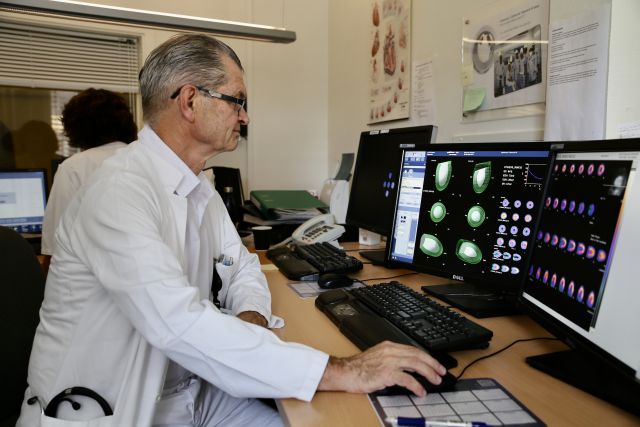Kardiolog Jan Hysing sitjande ved eit arbeidsbord. Han ser på ein dataskjerm kor ulike digitale tverrsnitt av ein pasients blodårer visast.