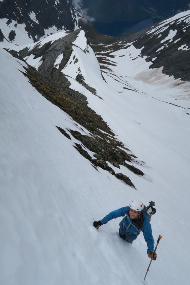 Naturgeograf Ørjan Søderblom er avbildet på fjelltur. Vi ser han på vei oppover en snøbrett fjellside, iført blå jakke og hvit hjelm. Han holder en skistav i den ene hånden.