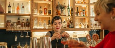 En kvinnelig bartender lager en drink til en gjest på baren
