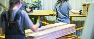Tre kvinners lager innendørspanel i en trevarefabrikk