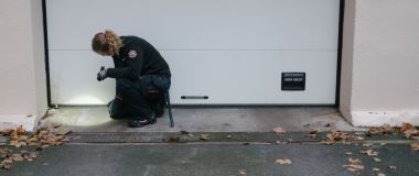 En skadedyrbekjemer ser under en garasjeport med lommelyktq