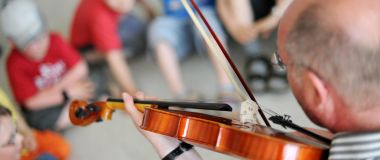 Musikkpedagog underviser elevene i å spille fiolin.