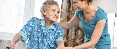 Pleiemedarbeider hjelper eldre kvinne