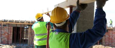 To tømrere på en byggeplass støtter en planke.